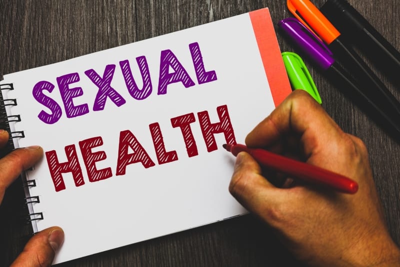 Hand writing the words "Sexual Health" on a notepad