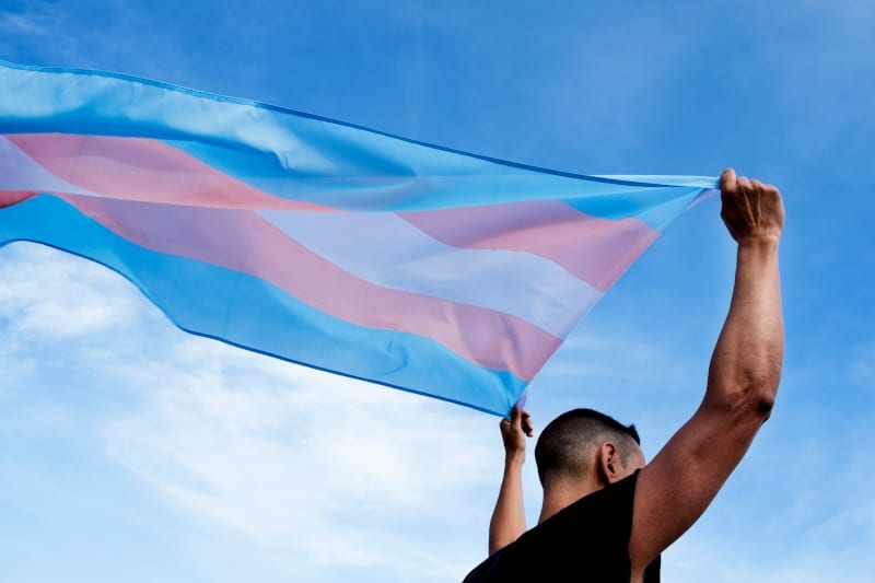 Ung person med et transgender pride-flagg