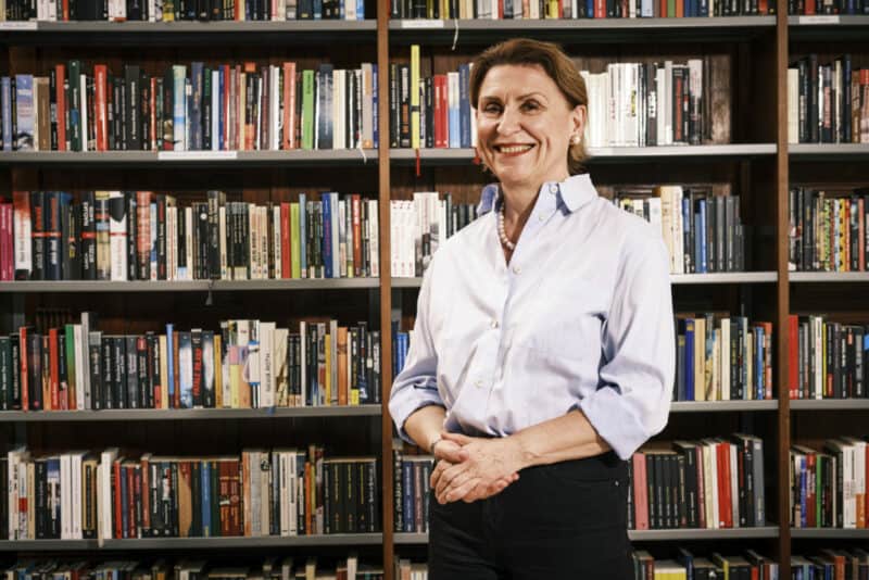 Image of Barbara Lison, smiling in front of a book shelf