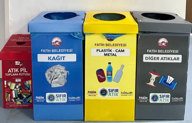 Four different recycling bins next to each other, each has a different color